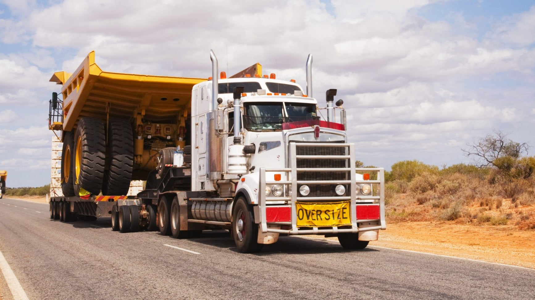 Oversize Banner attached to Kenworth Heavy Haulage Truck Towing Cat Dump Truck