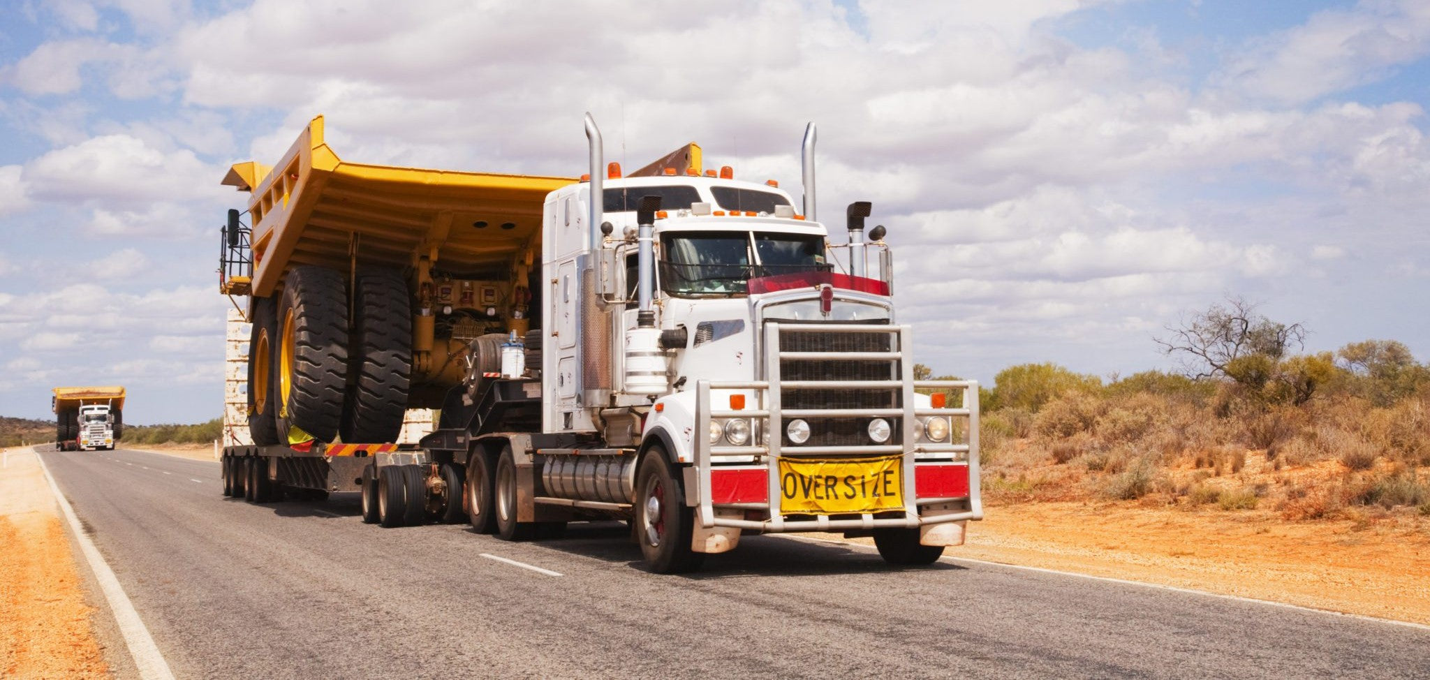 Oversize Banner attached to Kenworth Heavy Haulage Truck Towing Cat Dump Truck